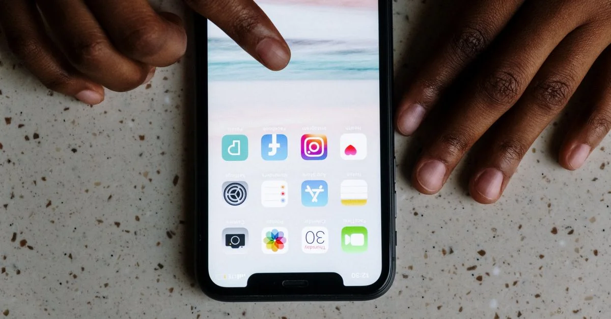 Vue en gros plan des mains interagissant avec des applications de médias sociaux sur l'écran d'un smartphone.