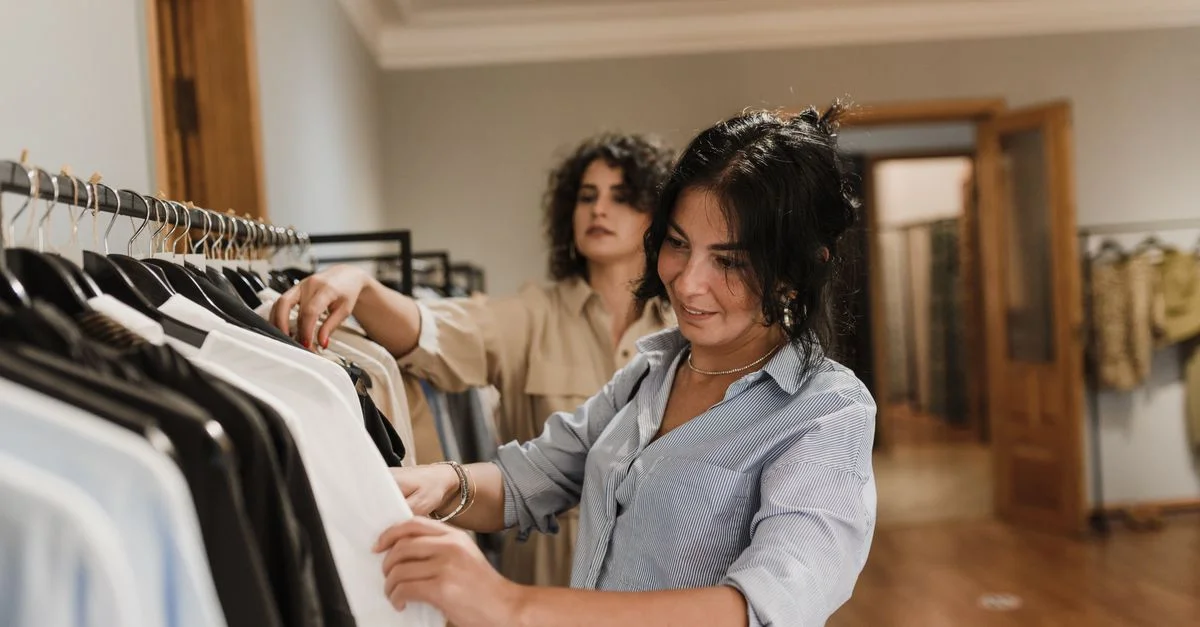 Deux femmes parcourant des cintres de vêtements dans un intérieur de boutique élégant.
