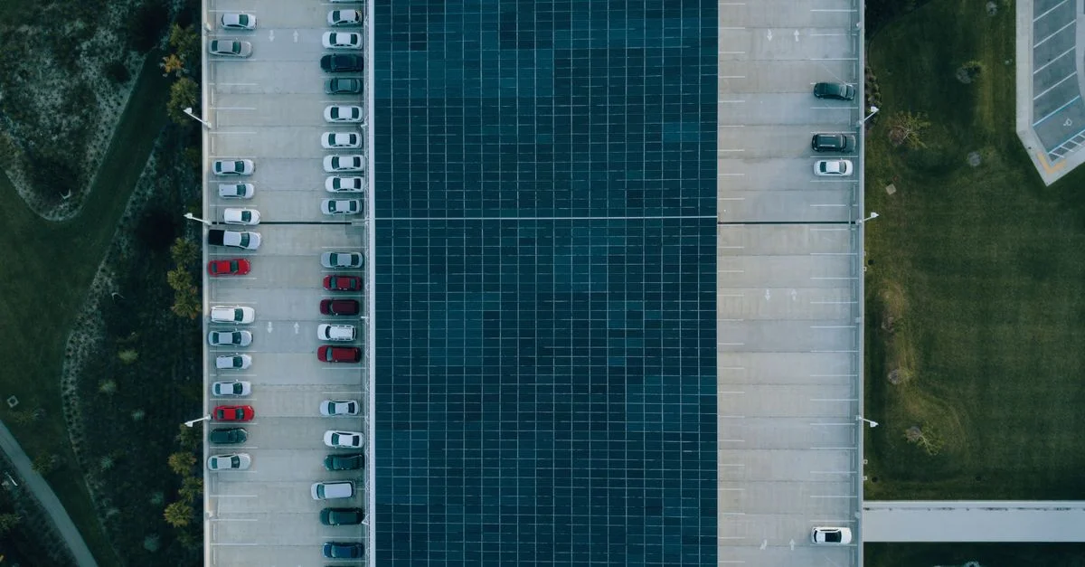 Vue du dessus d'un parking avec des voitures et des panneaux solaires, mettant en avant la durabilité urbaine.