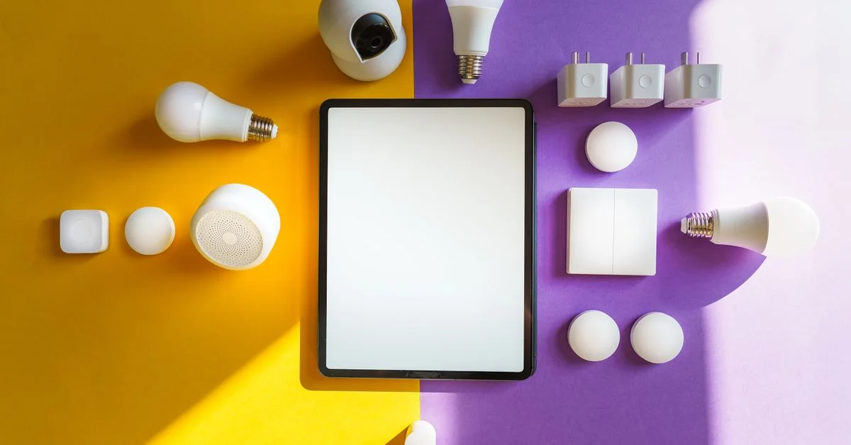 Vue de dessus des appareils de maison intelligente et d'une tablette sur un fond jaune et violet divisé.