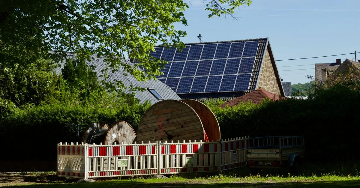Grange équipée de panneaux solaires et d'enrouleurs de câbles dans un cadre champêtre rustique.
