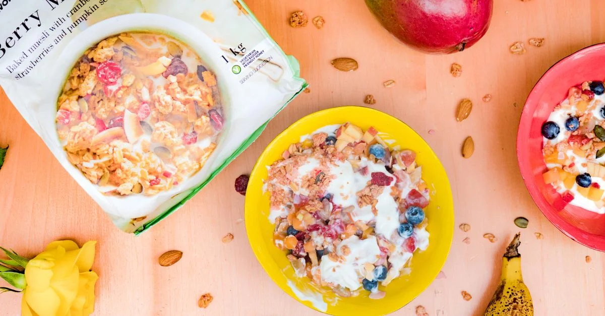 Des bols colorés de muesli crémeux et de fruits frais sur une table en bois, parfaits pour un petit-déjeuner sain.