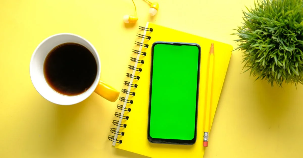 Ensemble de bureau minimaliste jaune vif avec carnet, smartphone, café et plante.